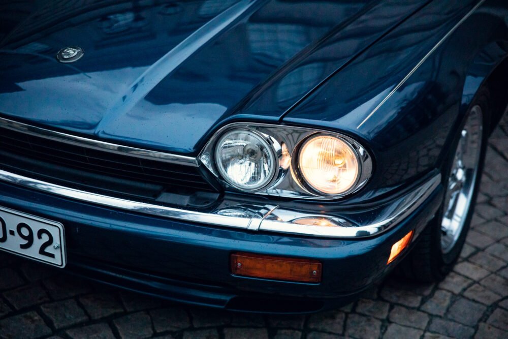 Close-up of vintage blue car's illuminated headlights.