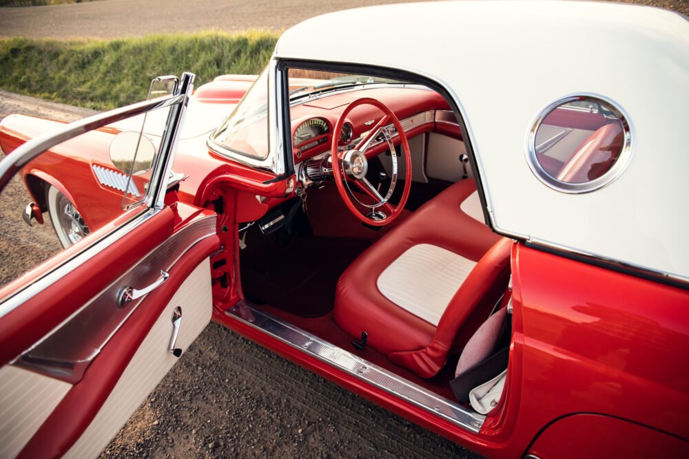 Vintage red convertible with white details, open door view.