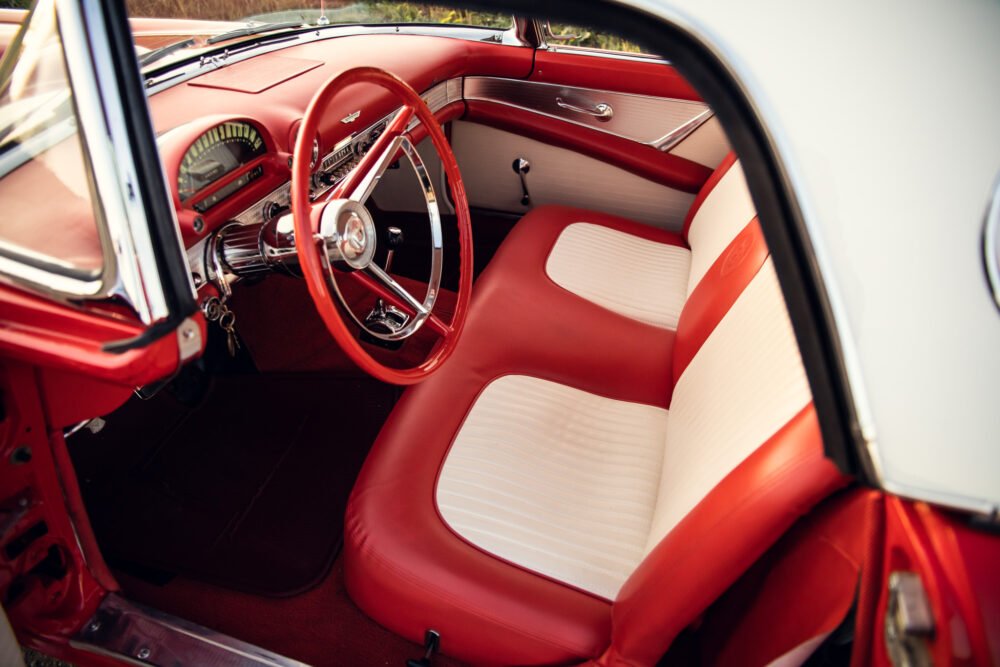 Vintage red car interior with white seats.