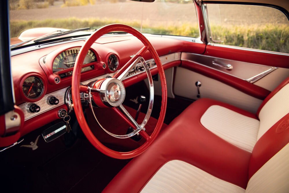 Vintage red car interior with classic steering wheel.