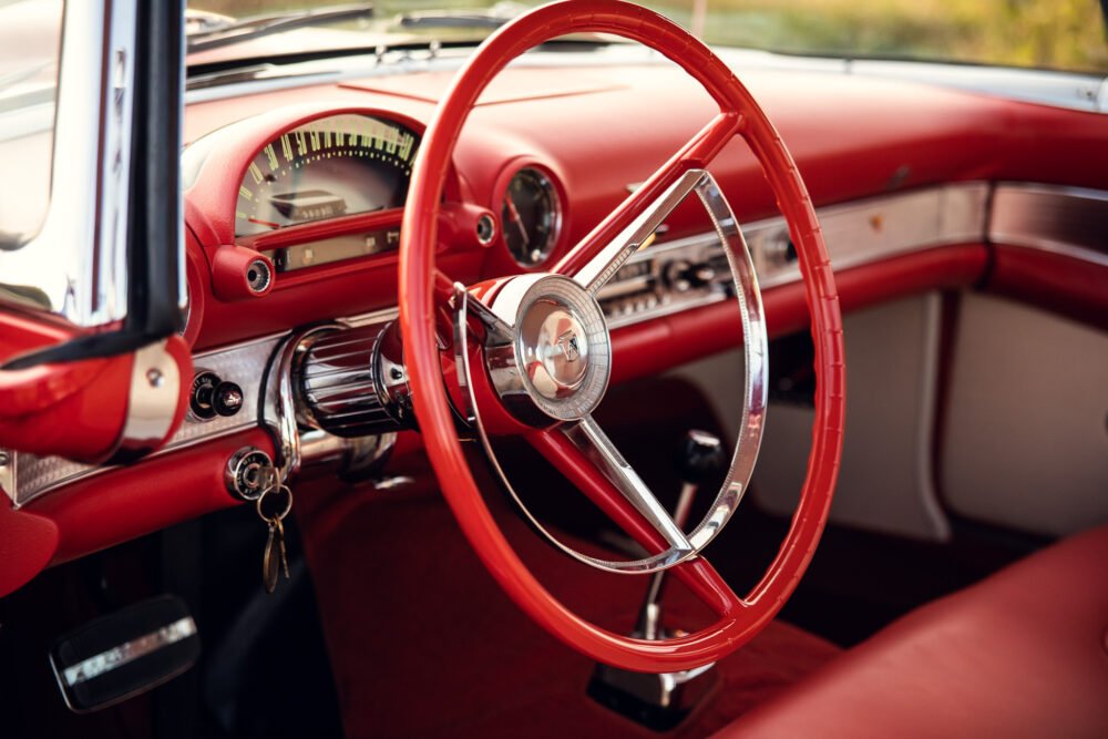 Vintage red car interior with steering wheel.