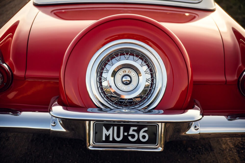 Close-up of classic red car's spare tire and bumper.