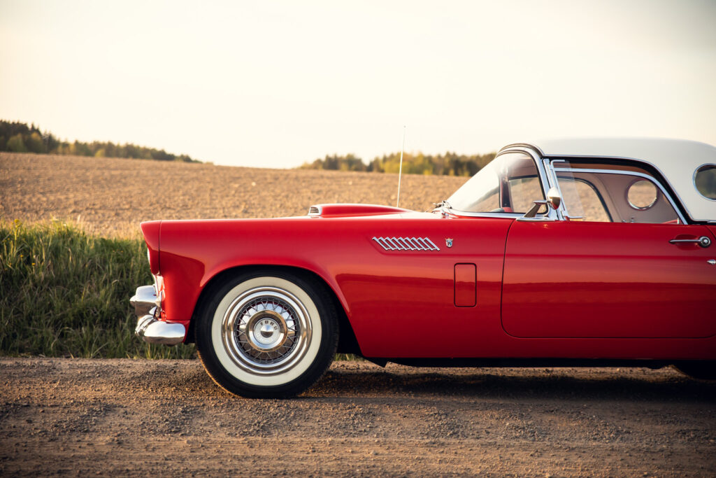 Vintage red car parked in rural setting.