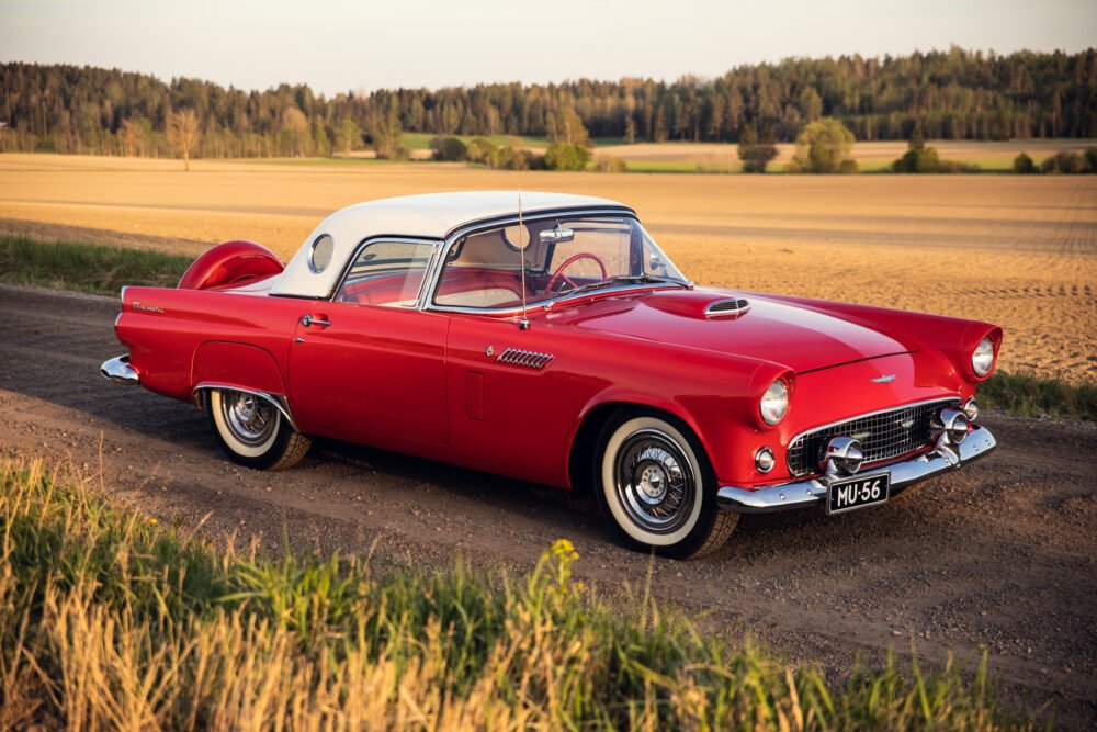 Vintage red Thunderbird car on countryside road.