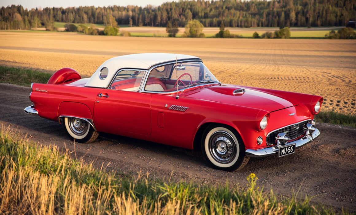 Vintage red Thunderbird on rural road at sunset.