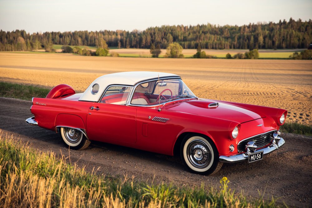 Vintage red Thunderbird car in rural setting.