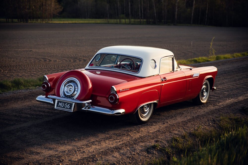Vintage red and white Thunderbird on dirt road.