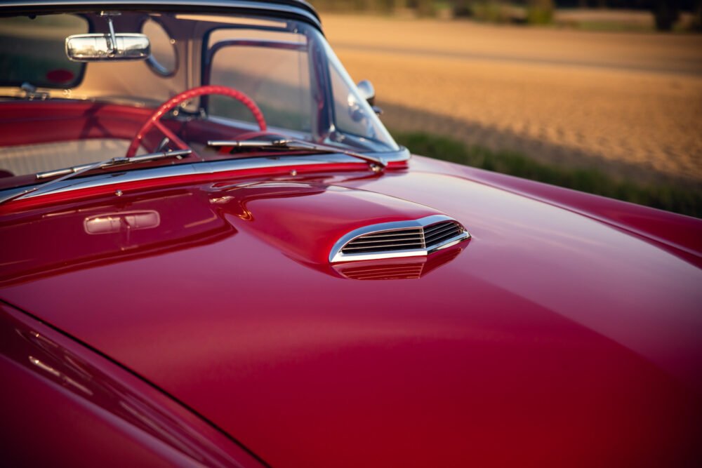 Red vintage convertible car at sunset.