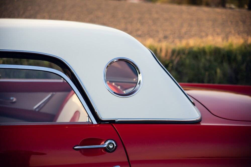 Close-up of vintage red car with circular window.