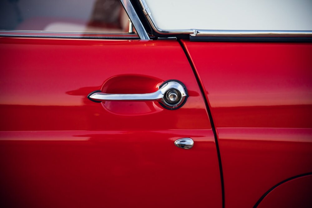 Close-up of a red vintage car door handle.