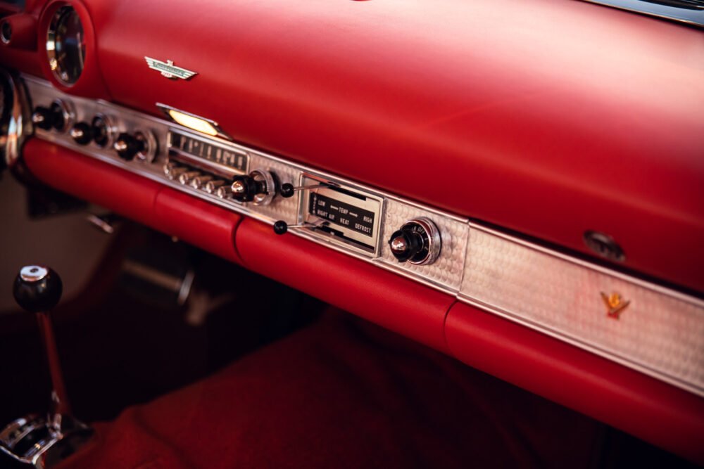 Vintage red car dashboard with chrome details.