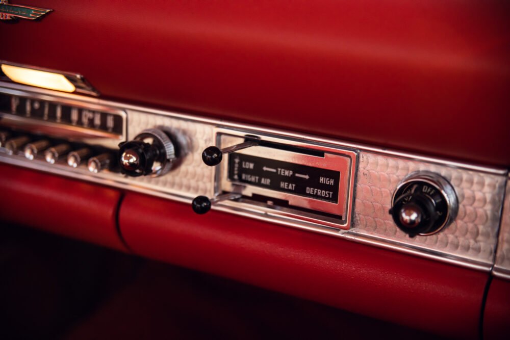 Vintage car dashboard with red interior and climate controls.