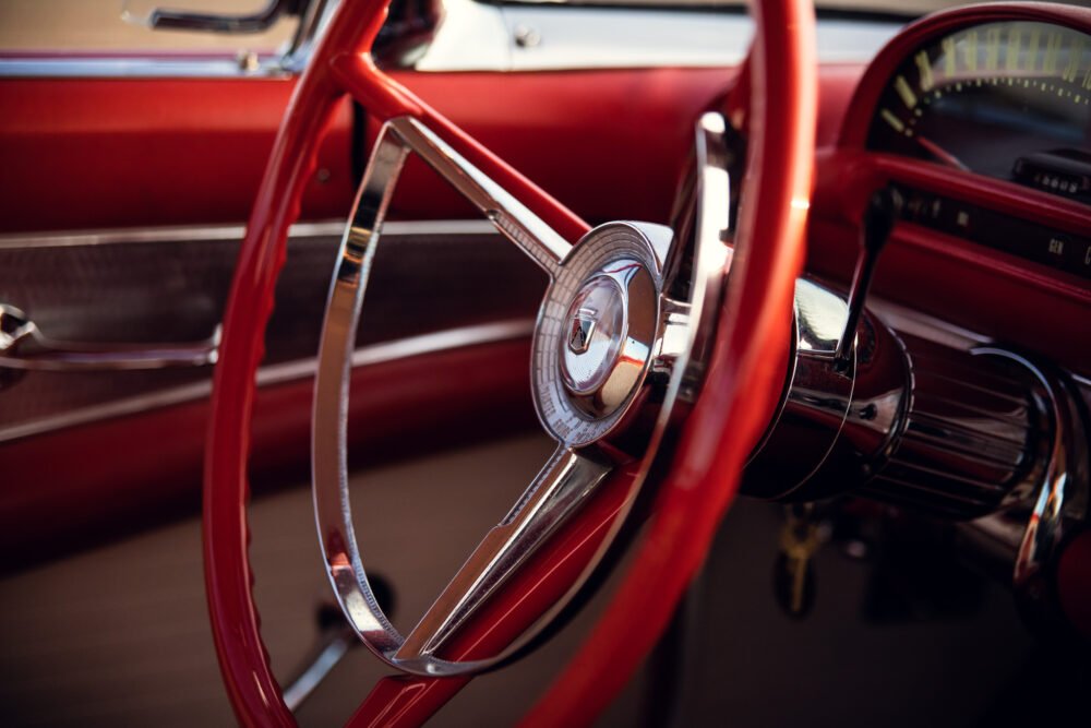 Vintage red car steering wheel and dashboard.