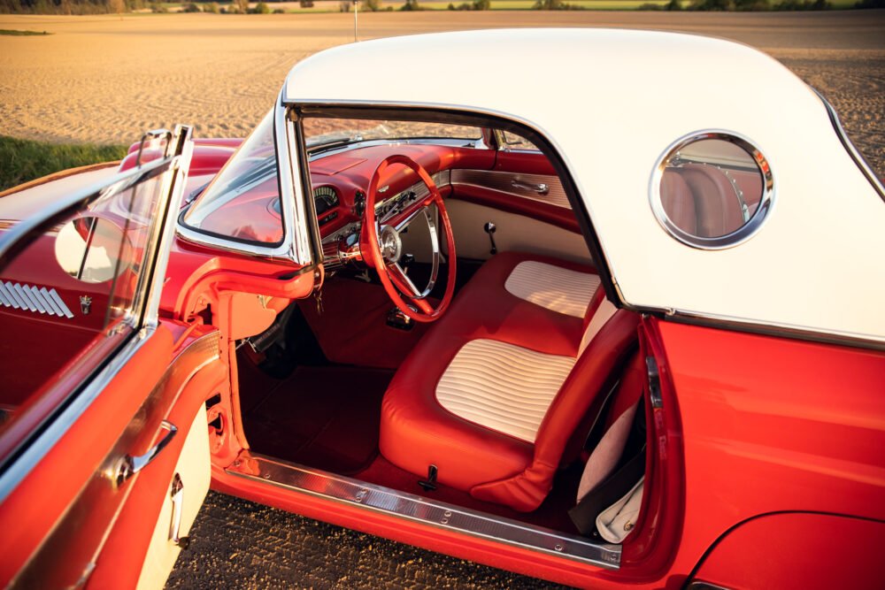 Vintage red convertible car interior, sunset lighting.