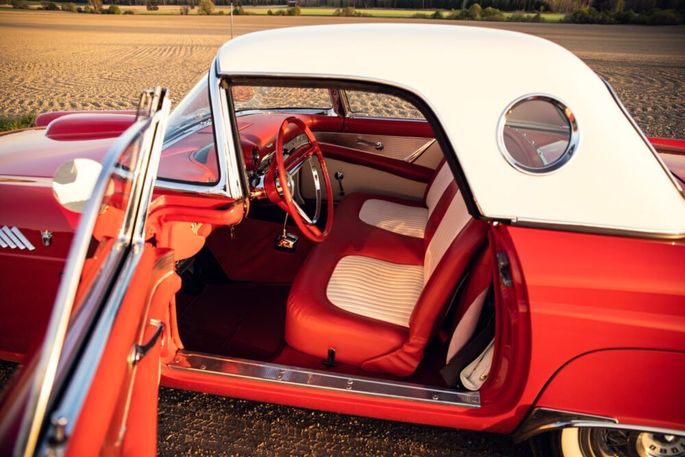 Vintage red convertible car with white top, interior view.