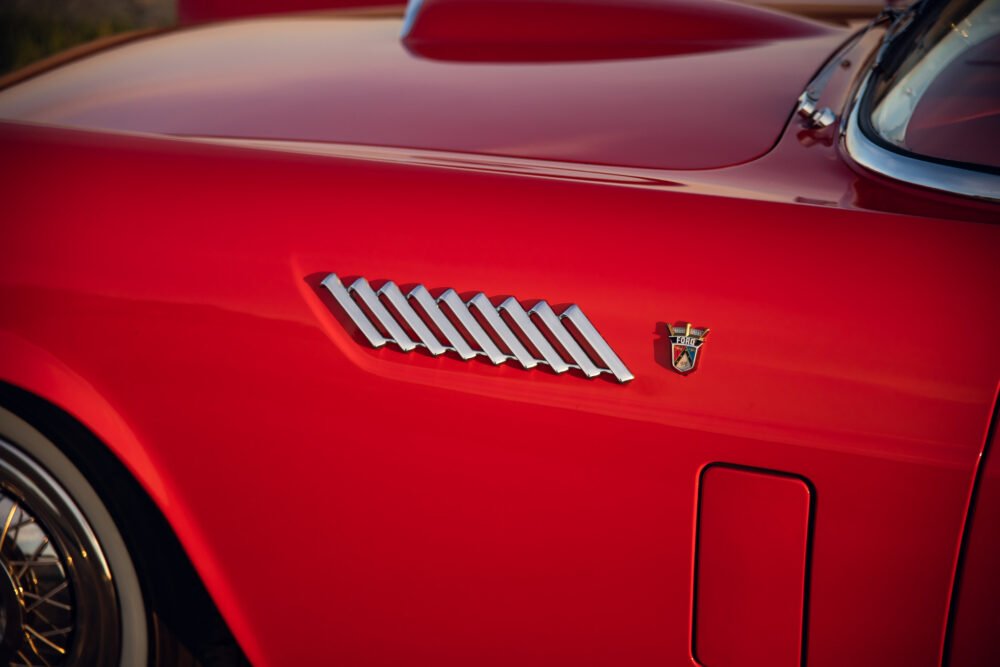 Red vintage car's emblem and sleek side detail.