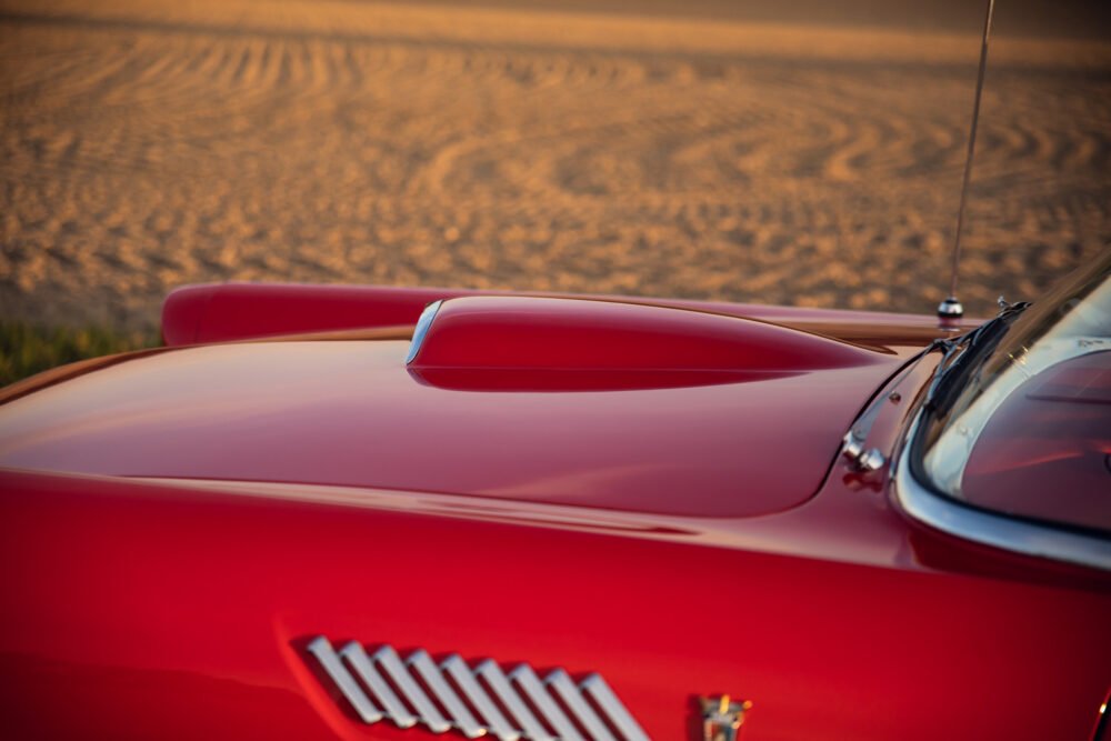Red vintage car on sandy desert background.