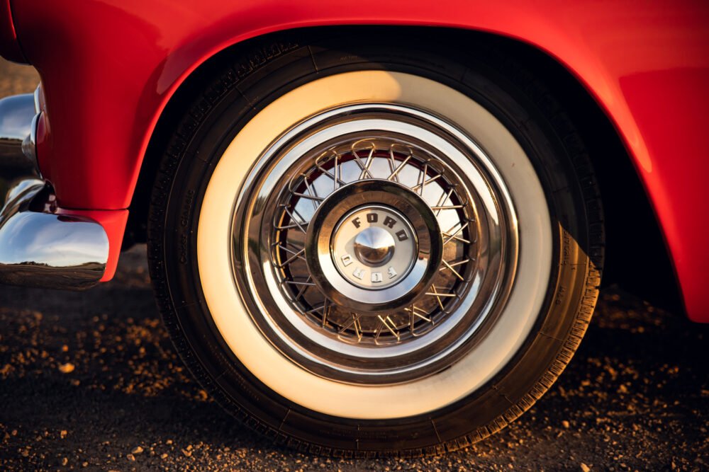 Close-up of vintage Ford wheel on classic red car.