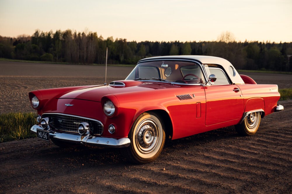 Vintage red Ford Thunderbird on rural road.