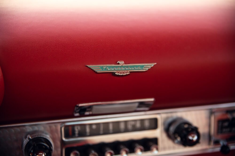 Close-up of Ford Thunderbird logo on red dashboard.