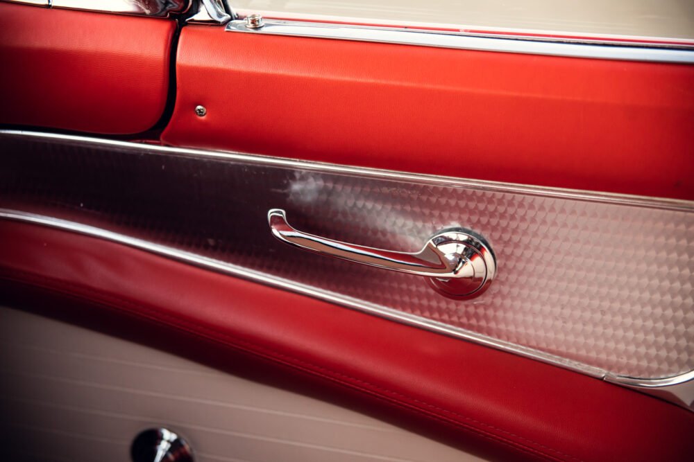 Close-up of vintage car's red door and chrome handle.