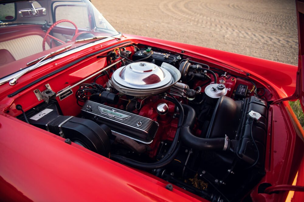 Red classic car engine and open hood detail.