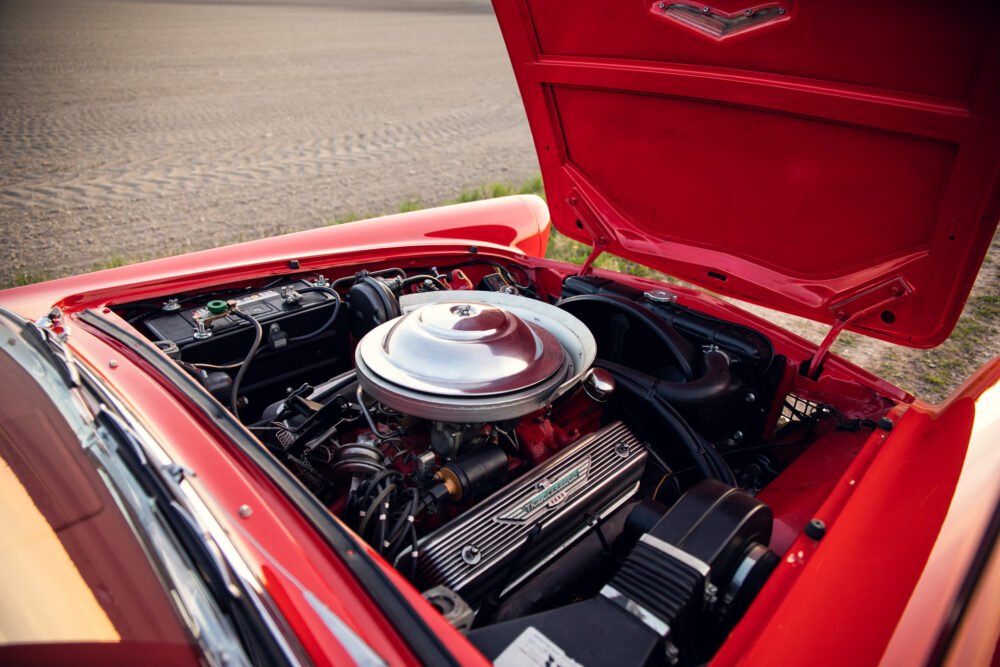 Classic red car engine bay open, detailed view.