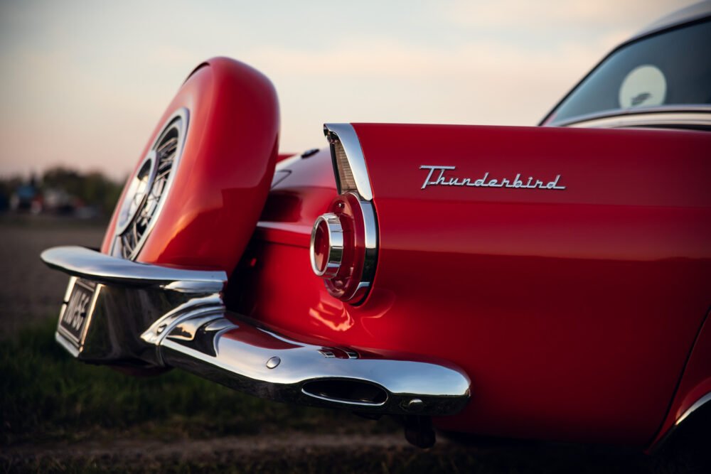 Red vintage Thunderbird car tail fin at dusk.