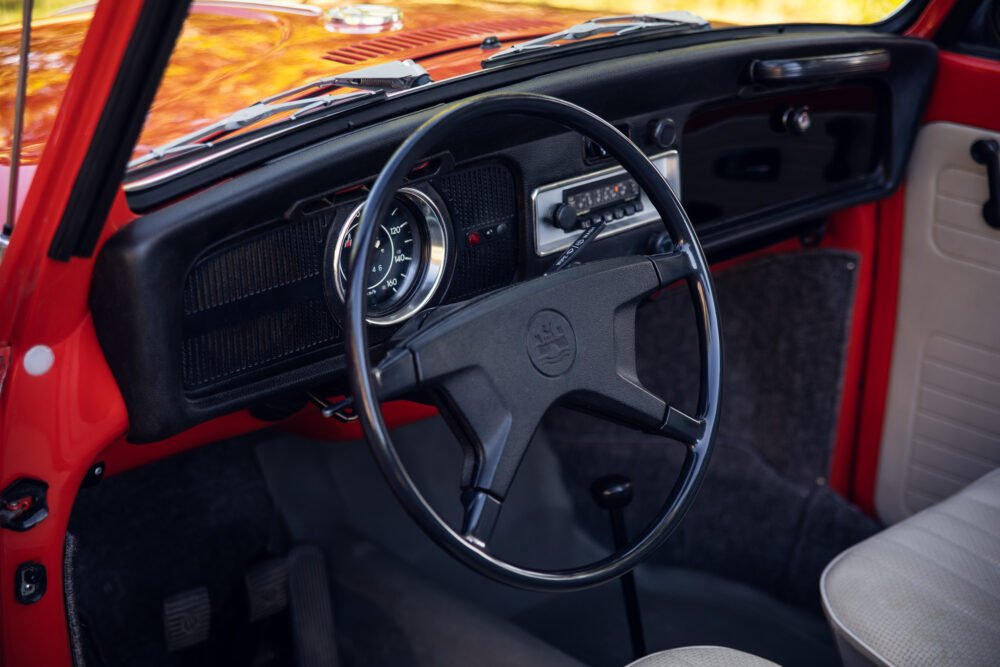 Vintage red car interior with steering wheel and dashboard.
