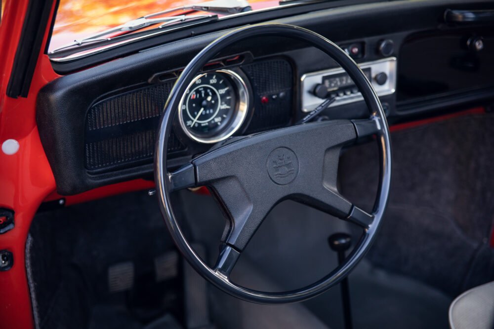 Vintage red car interior, classic steering wheel and dashboard.