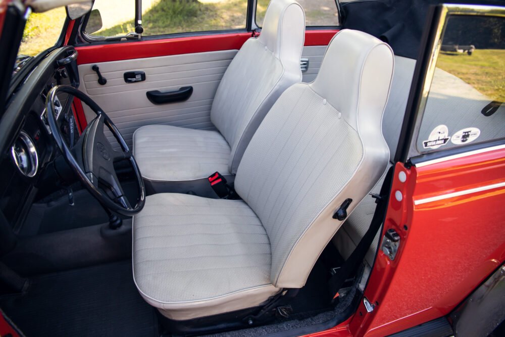 Interior of vintage red car with white seats.