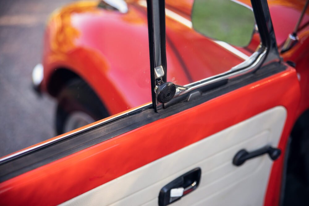 Close-up of vintage car door and red exterior.
