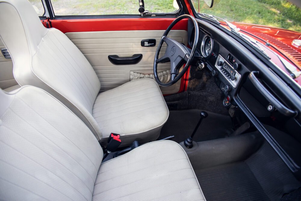 Vintage car interior with white seats and red dashboard.