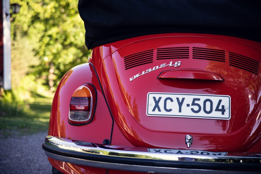 Red vintage Volkswagen Beetle, rear view, license plate visible.
