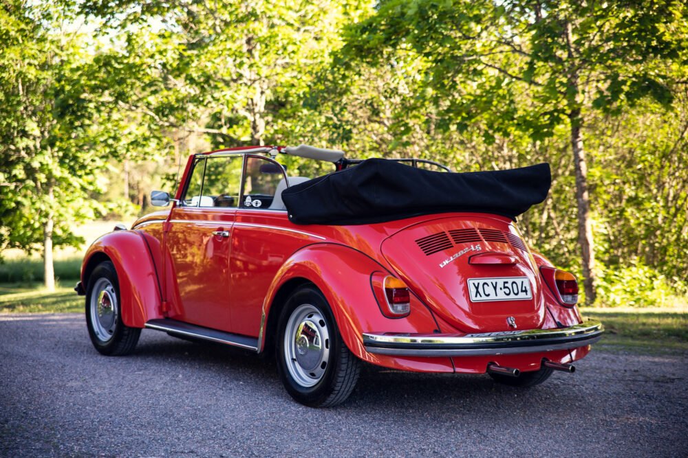 Red vintage convertible Beetle parked outdoors.