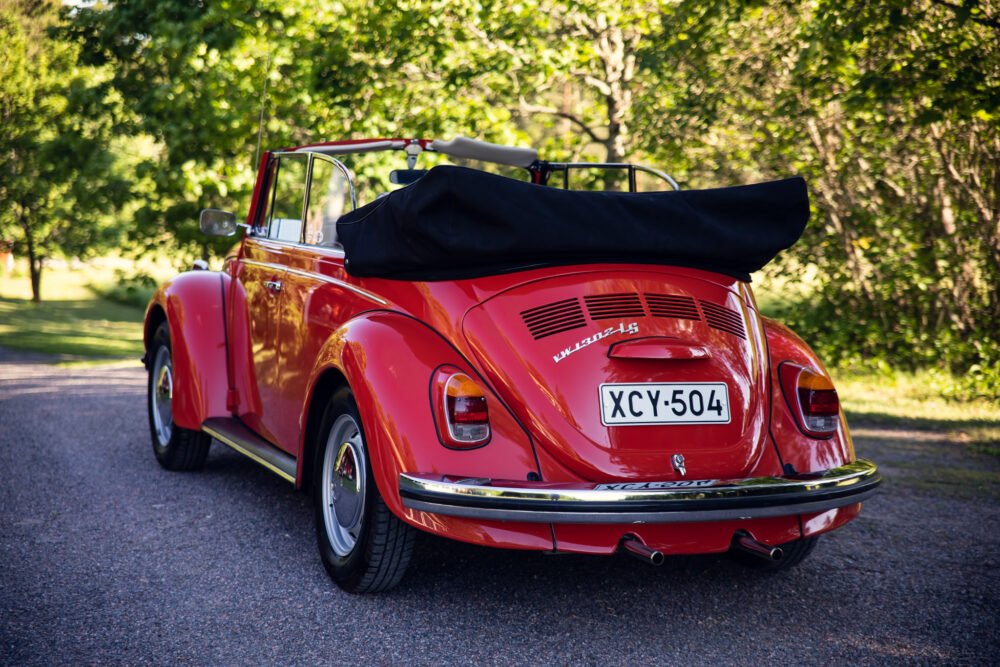 Red vintage convertible Volkswagen Beetle parked on road.