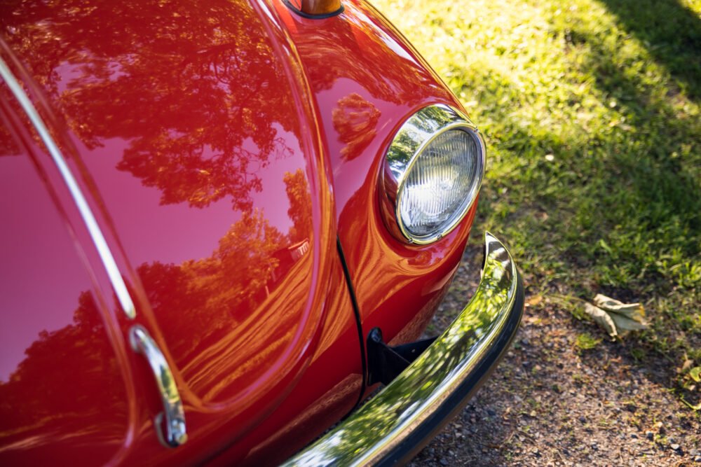 Close-up of a vibrant red vintage car's headlight.