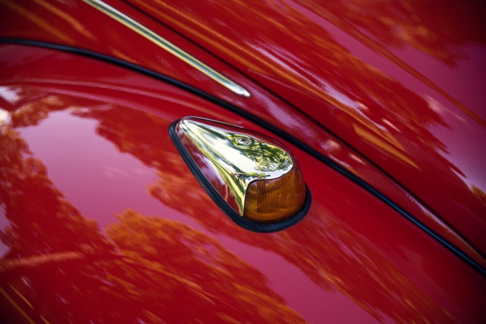 Close-up of vintage car's red hood and chrome detail.