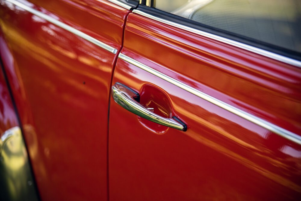Close-up of red vintage car door handle.
