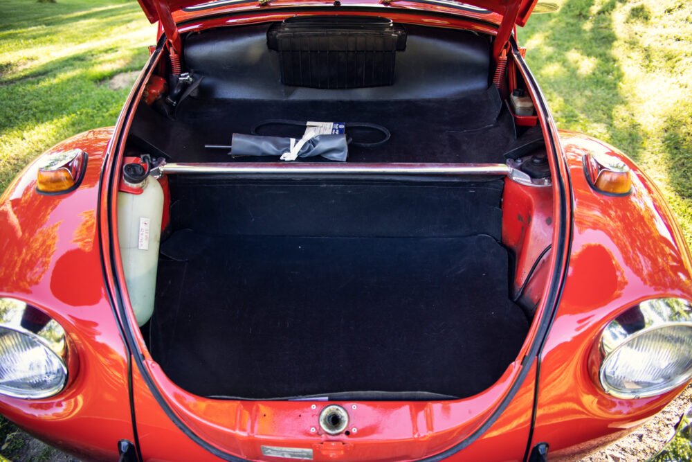 Open trunk of vintage red car showing contents.