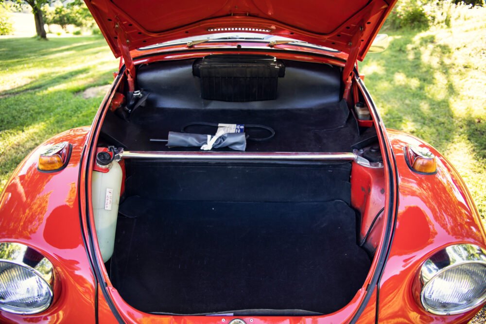 Red vintage car with open trunk showing tools.