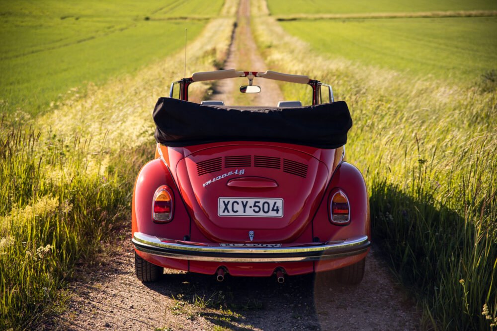 Red vintage convertible car on rural road.