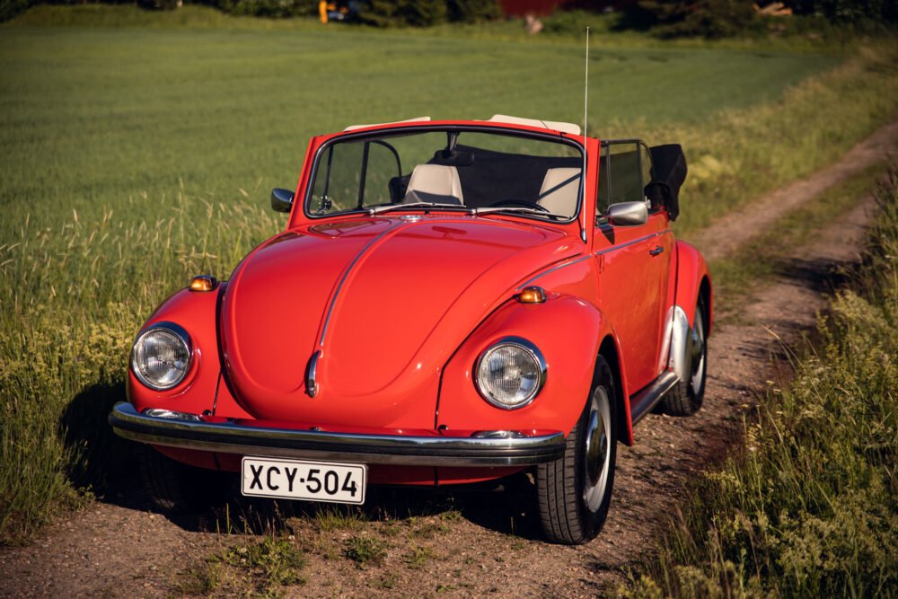 Red vintage convertible Beetle in sunny countryside.