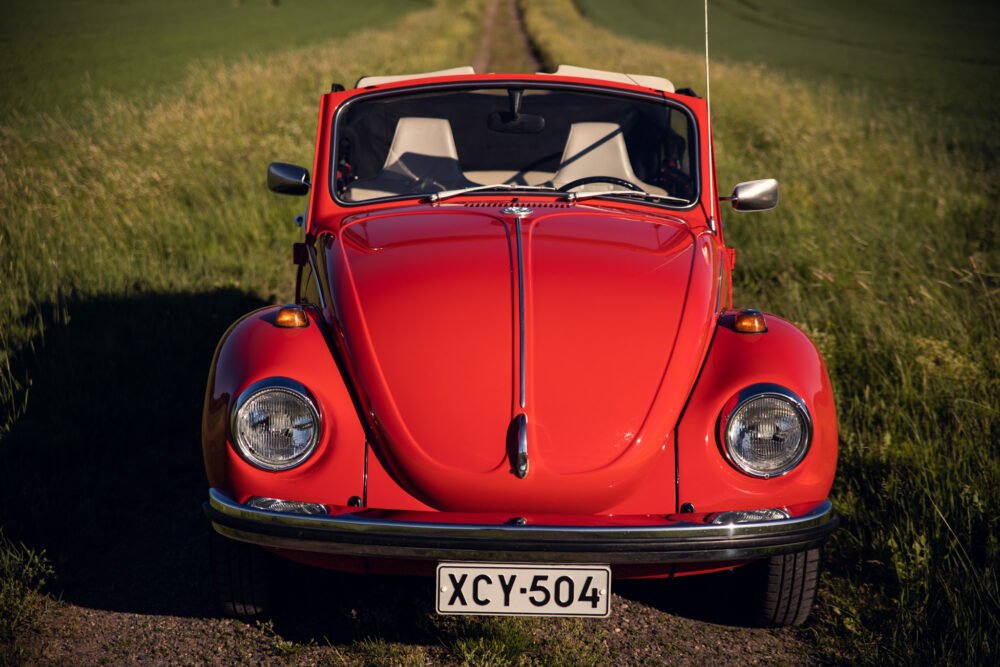 Red vintage Volkswagen Beetle on country road.