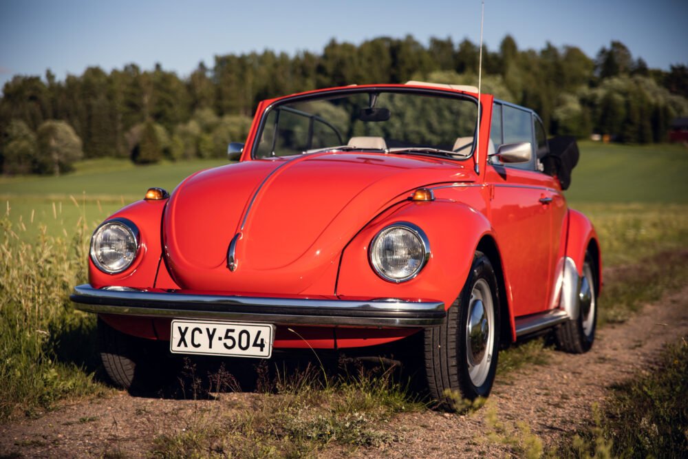 Red vintage Volkswagen Beetle in a sunny field