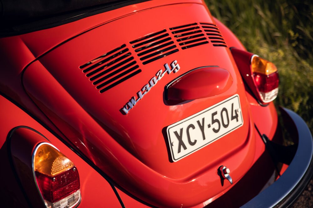 Red vintage Volkswagen Beetle, rear view in sunlight.