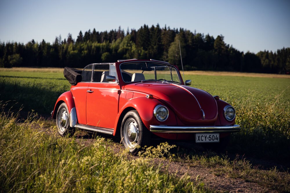Red vintage convertible Volkswagen Beetle in countryside.