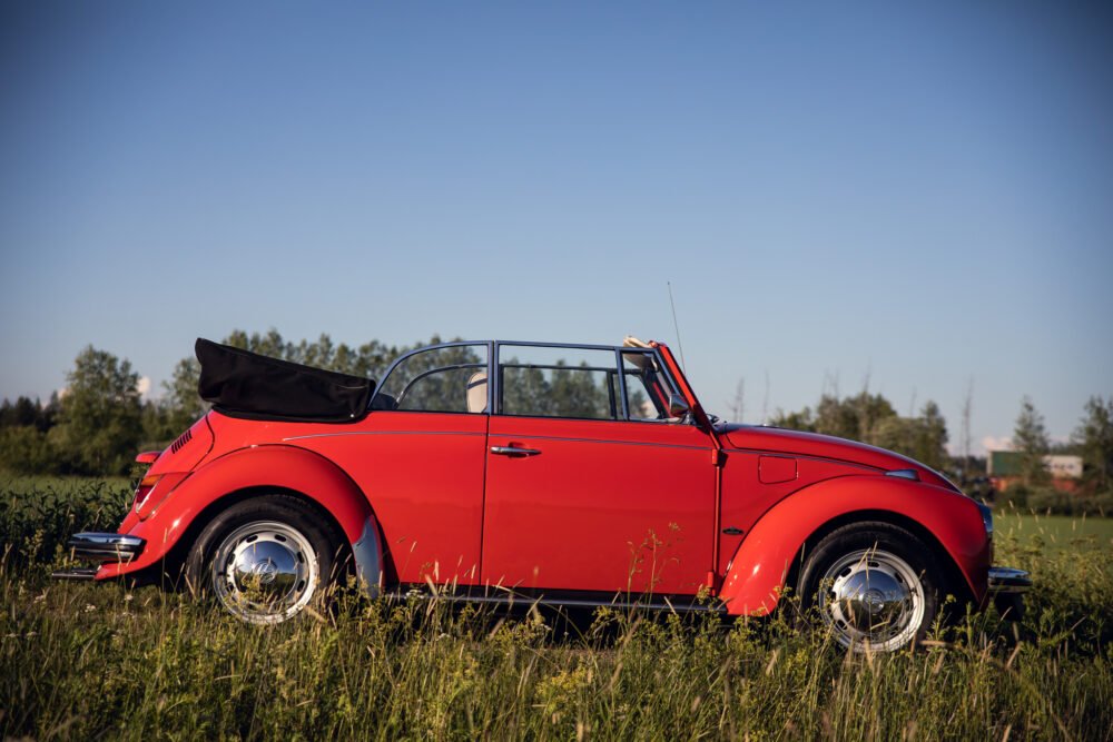 Red vintage convertible car in grassy field.