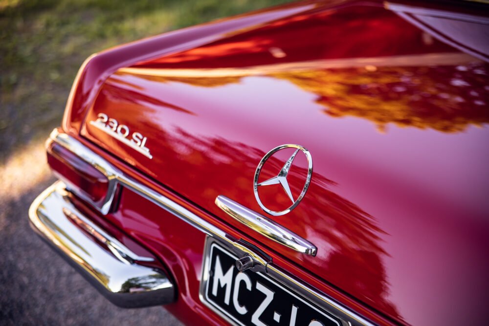 Red Mercedes 230SL with logo, vintage car close-up.