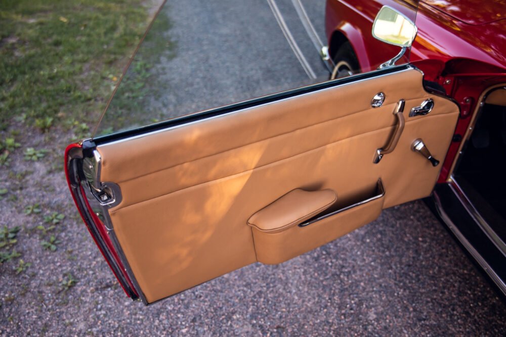 Vintage car's open door with tan leather interior.